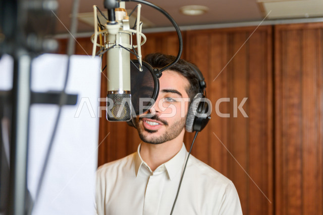 مذيع سعودي داخل الاستديو ، تسجيل الصوت من خلال المايكروفون ،  استديو تسجيل صوتي ، بث مباشر ، فريق الاعداد ، الاذاعة الصوتية ، نشرات اخبارية