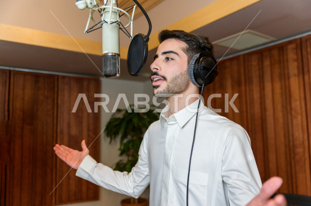 Saudi broadcaster inside the studio, recording audio through the microphone, studio audio recording, live broadcast, preparation team, audio broadcast, news bulletins