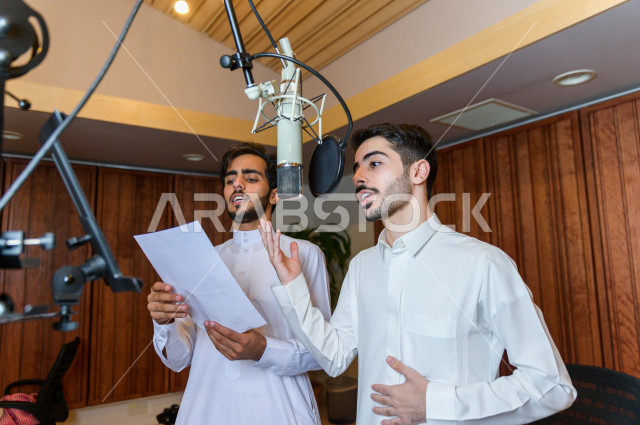 مذيعان سعوديان داخل الاستديو ، تسجيل الصوت من خلال المايكروفون ،  استديو تسجيل صوتي ، بث مباشر ، فريق الاعداد ، الاذاعة الصوتية ، نشرات اخبارية