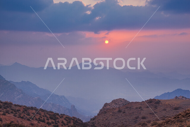 Misty and cloudy skies above the peaks and mountains at sunset, terrain and mountainous heights in the city of Taif, winding rocky roads, wild green plants in tourist areas in the Kingdom of Saudi Arabia, famous tourist attractions
