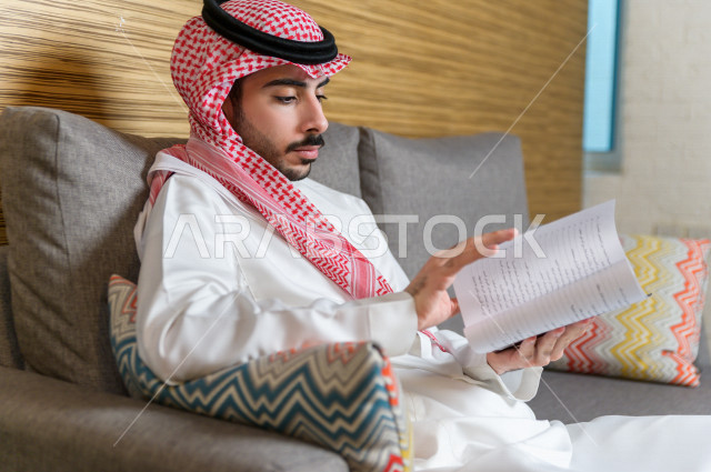شاب سعودي خليجي مثقف يقضي وقته في المكتبة و يقرأ الكتب ، قراءه كتب ،  الدراسة في المكتبة