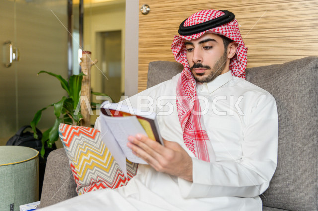 شاب سعودي خليجي مثقف يقضي وقته في المكتبة و يقرأ الكتب ، قراءه كتب ،  الدراسة في المكتبة