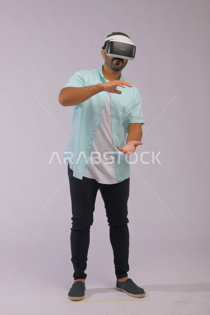 Exploring new worlds using virtual reality glasses, a portrait of a Saudi Gulf Arab man wearing casual summer clothes and wearing 3D glasses, using technology and modern technology, full body portrait, white background
