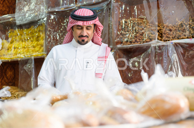 رجل سعودي خليجي يتبضع في قسم المخبوزات داخل السوبرماركت ، شراء الاحتياجات المنزلية ، السلع والمواد غذائية المختلفة ، مستلزمات المستهلك