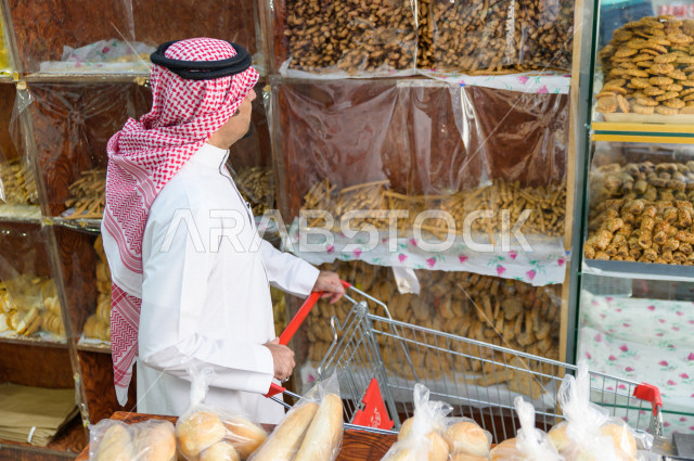 رجل سعودي خليجي يتبضع في قسم المخبوزات داخل السوبرماركت ، شراء الاحتياجات المنزلية ، السلع والمواد غذائية المختلفة ، مستلزمات المستهلك