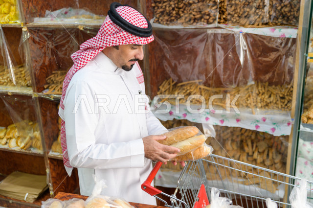 رجل سعودي خليجي يتبضع في قسم المخبوزات داخل السوبرماركت ، شراء الاحتياجات المنزلية ، السلع والمواد غذائية المختلفة ، مستلزمات المستهلك