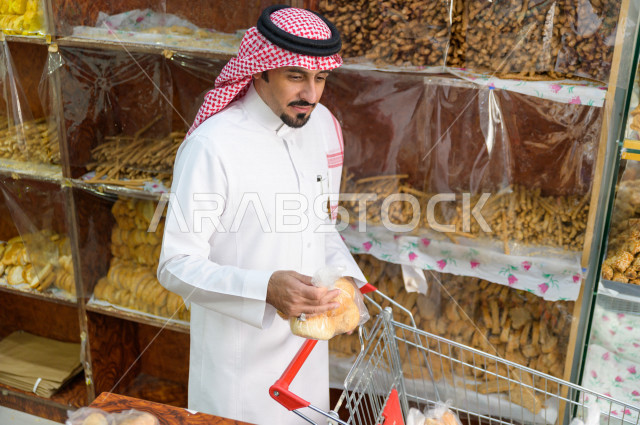 رجل سعودي خليجي يتبضع في قسم المخبوزات داخل السوبرماركت ، شراء الاحتياجات المنزلية ، السلع والمواد غذائية المختلفة ، مستلزمات المستهلك