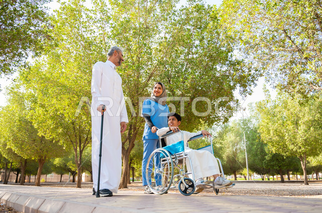 ذوي الهمم والإعاقات الحركية، رجل كبير السن عربي خليجي سعودي يرتدي الزي التقليدي يستخدم العكاز للمساعدة على السير مع ابنه، ممرضة تهتم بولد من ذوي الاحتياجات الخاصة, المشي في الحدائق العامة تحت ضوء الشمس, مفهوم الرعاية الصحية والاعتناء بالمرضى والمعاقين.