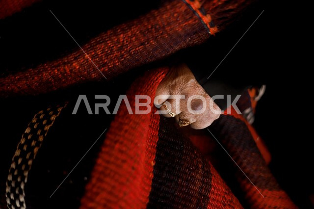 غزل الصوف لصنع السجاد ,صورة مقربة لسيدة عربية خليجية سعودية تقوم بأشغال يدوية, حياكة  الانسجة والقماش، صناعات تقليدية شعبية، حرف يدوية سعودية قديمة، فعاليات مدينة العلا