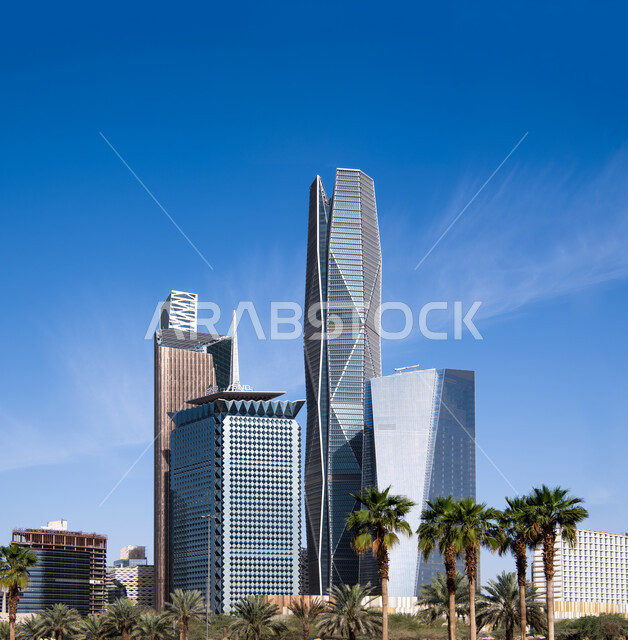 Green palm trees surrounding the King Abdullah Financial Center (CAFD) in Riyadh, the ideal destination for finance and business with international standards, distinctive arts and architectural designs for economic towers and skyscrapers, leading high-end companies in banking services and financial technology.