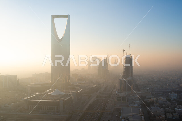 Working on the growth and development of engineering construction in the Kingdom of Saudi Arabia, the tourist façade to attract visitors from all over the world, the advanced architecture of the Kingdom Tower building in the city of Riyadh, famous tourist places and landmarks, skyscrapers and facilities during the day.