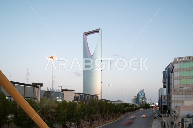معالم سياحية مشهورة في وقت النهار, تطور وتنمية العمران بالمملكة العربية السعودية, حركة مرور السيارات في طريق الملك فهد, أشجار النخيل الخضراء، الهندسة المعمارية الفنية لمبنى برج المملكه في مدينة الرياض