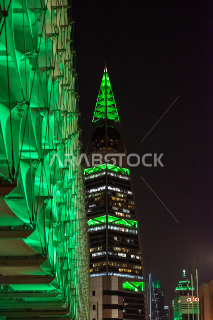 ذكرى توحيد المملكة العربية السعودية، صورة من الأسفل لبرج الفيصلية في حي العليا في مدينة الرياض، إضاءة باللون الاخضر احتفالا باليوم الوطني السعودي 23 سبتمبر، أبراج الرياض وناطحات السحاب تحتفل بيوم العلم السعودي 11 مارس