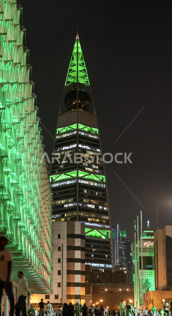 ذكرى توحيد المملكة العربية السعودية، صورة من الأسفل لبرج الفيصلية في حي العليا في مدينة الرياض، إضاءة باللون الاخضر احتفالا باليوم الوطني السعودي 23 سبتمبر، الازدحام أمام أبراج الرياض وناطحات السحاب للاحفال بيوم العلم السعودي 11 مارس