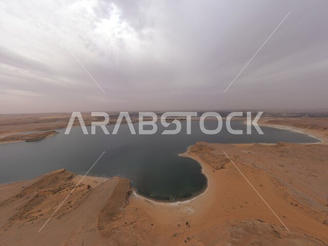 The artificial lake of Duma in Dumat al-Jandal in the Kingdom of Saudi Arabia, high golden sand hills, famous natural tourist places, a view of the cloudy sky