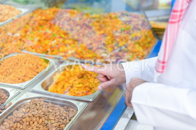 رجل سعودي خليجي يتبضع في قسم المكسرات داخل السوبرماركت ، شراء الاحتياجات المنزلية ، السلع والمواد غذائية المختلفة ، مستلزمات المستهلك