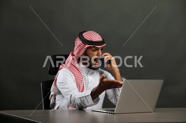 الشعور بالانزعاج والإثارة، إيماءات الصراخ الشديد والغضب، بورتريه لرجل أعمال عربي  سعودي خليجي يرتدي الشماغ والثوب التقليدي يجري مكالمة هاتفيه باستخدام الهاتف المحمول، حدوث مشكلة في مشروع العمل، التهيج والتوتر والضغط، خلفية رمادية .