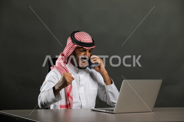 الحماس والقيام بصفقات ناجحة مع العملاء عبر اللابتوب, بورتريه مقرب لرجل عربي خليجي سعودي يرتدي الثوب التقليدي والشماغ يجلس بإيماءات الفوز والنصر وتحقيق أهداف العمل الاداري, السرور والبشاشة وإنجاز المهام المطلوبة, خلفية سوداء