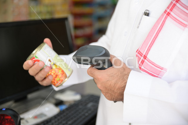 A Saudi-Gulf man pricing his purchasing needs at the accountant, buying household needs inside the supermarket, various commodities and foodstuffs, consumer supplies