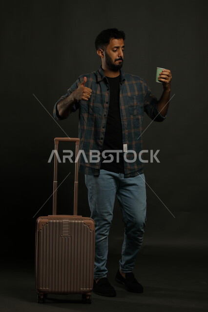 ايماءات الاعجاب والموافقة، بورتريه لرجل عربي سعودي خليجي يرتدي الزي الكاجوال يستعد لقضاء رحلة سياحية خارج البلاد، احتساء المشروبات الساخنة، الاستمتاع بالعطلة الصيفبة، استكشاف ثقافات وعادات جديدة، خلفية رمادي