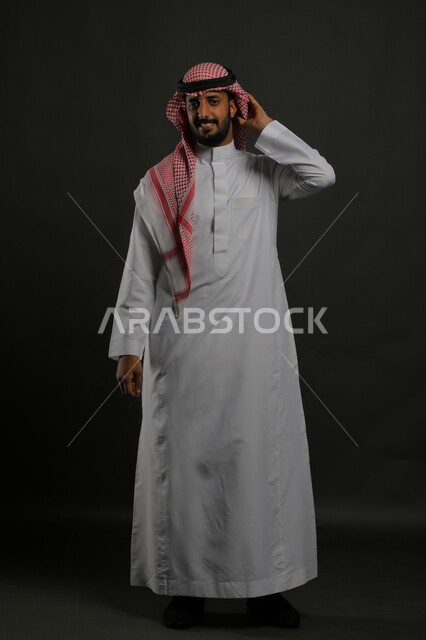 Standing upright and disciplined, self-confidence and a feeling of strength, taking care of the external appearance, a portrait of a Saudi Gulf Arab man wearing the traditional dress and shemagh and looking at the camera seriously, the concept of elegance and masculinity, a full-body portrait, gray background