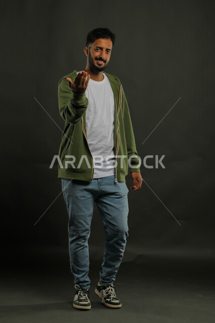 التحضير لمشروع التخرج ، بورتريه لرجل عربي خليجي سعودي يرتدي الزي الكاجوال ويشير بيده لأحد ما، شرح العروض التقديمية بإيماءات السرور، ايماءات الاقتراب وطلب التقدم، صورة الجسم بالطول الكامل، خلفية سوداء