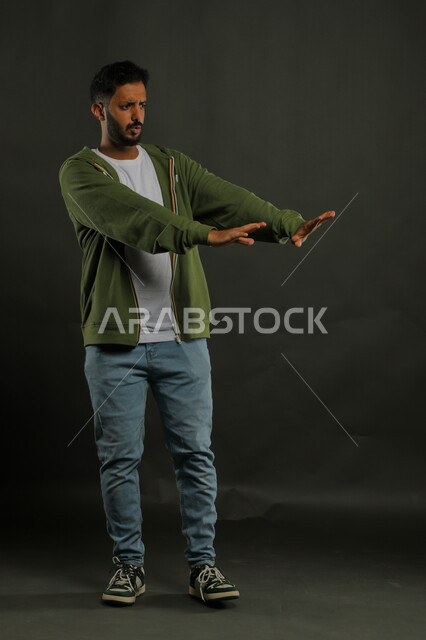 طلب الابتعاد وعدم الاقتراب, حماية النفس من ضرر خارجي, رفع اليدين بإيماءات الاحتياط والقلق والتوقف , بورتريه لرجل عربي خليجي سعودي يرتدي الزي الكاجوال و يقف بحذر, صورة الجسم بالطول الكامل, خلفية سوداء