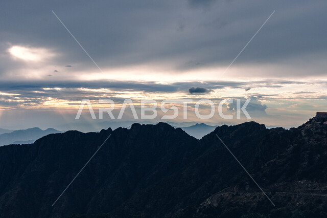 البيئة الطبيعيه في المرتفعات والهضاب، لحظات غروب الشمس فوق جبال السودة بمنطقة عسير جنوب غرب المملكة العربية السعودية، منظر خلاب للسماء الملبدة بالغيوم، الأماكن والمعالم السياحية المشهورة