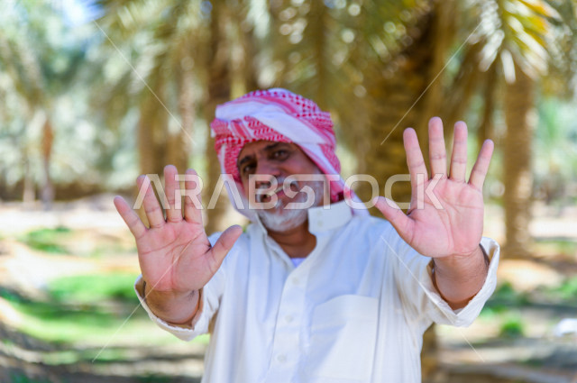 مزارع سعودي خليجي بايمائات و تعابير وجه مختلفه ، يبذل مجهود كبير في حصاد التمور و الاهتمام باشجار النخيل  ، الموسم الزراعي ، موسم جني محصول التمور في المناطق الزراعية ، مزارع النخيل المثمرة في المملكة العربية السعودية ، مزارع لانتاج التمور ، المناطق الزرا