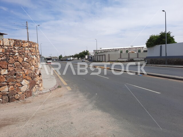 حركة مرور السيارات والحافلات في الشوارع في وضح النهار، الطرق المعبدة والأرصفة الإسفلتية، الجدران الحجرية في مدينة الطائف، الطبيعة الجبلية في المملكة العربية السعودية، أعمدة الإنارة في الطرقات