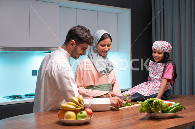  قضاء أوقات ممتعة مع الأبناء، ايماءات السعادة والسرور بالتعاون بين افراد العائلة داخل المطبخ, أم عربية خليجية سعودية محجبة تقوم بتعليم ابنتها الطبخ، مهارات وفنون الطبخ والتقطيع, مفهوم النظام الغذائي الصحي، إعداد وتحضير الطعام بمكونات طبيعية طازجة