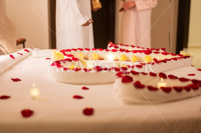 مشاعر الحب والود، زوجان يتبادلان الحديث، مفهوم الارتباط والإلفة، صورة مقربة لسرير مزين بالشموع والورود الحمراء على شكل قلب للاحتفال بيوم الفلنتاين، الاحتفال بذكرى الزواج، الاهتمام بالمناسبات الخاصة، تزيين غرفة النوم بطريقة رومانسية.