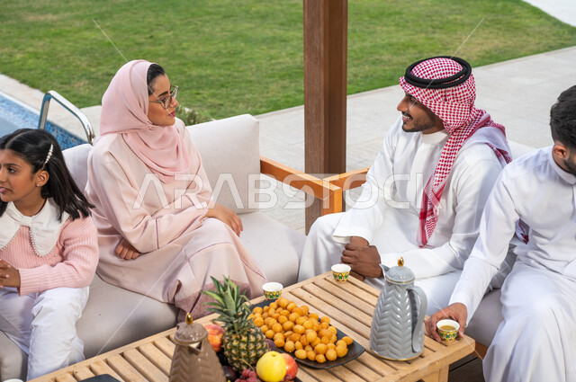 مشاركة الزوجة في الاحاديث والدردشات، قضاء أوقات عائلية ممتعه في أحد المنتجعات، عائلة عربيه خليجيه سعودية تجلس في إحدى الشاليهات للتسليه والترفيه، الترابط الاسري و صلة الرحم، التسامر والضحك مع الافراد، مفهوم النقاش والحوار بين الأهل