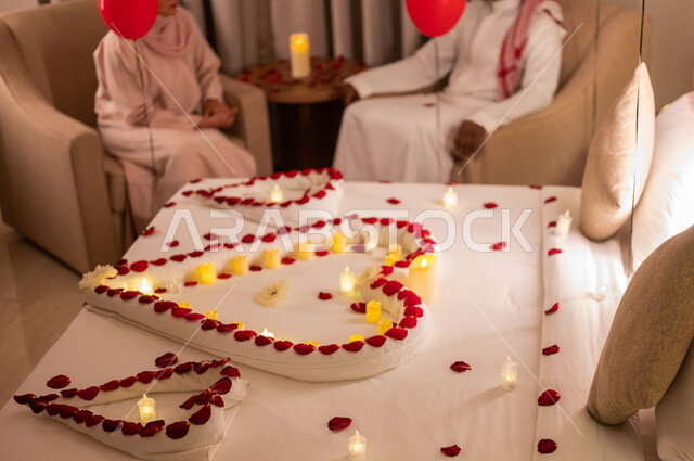 تبادل الأحاديث والتسامر بين الزوجين، تزيين غرفة النوم بطريقة رومانسية، احتفالات بذكرى الزواج، صورة مقربة لسرير مزين بالشموع والورود الحمراء على شكل قلب للاحتفال بيوم الفلنتاين، الاهتمام بالمناسبات الخاصة، مشاعر الحب والود، مفهوم الارتباط والإلفة.