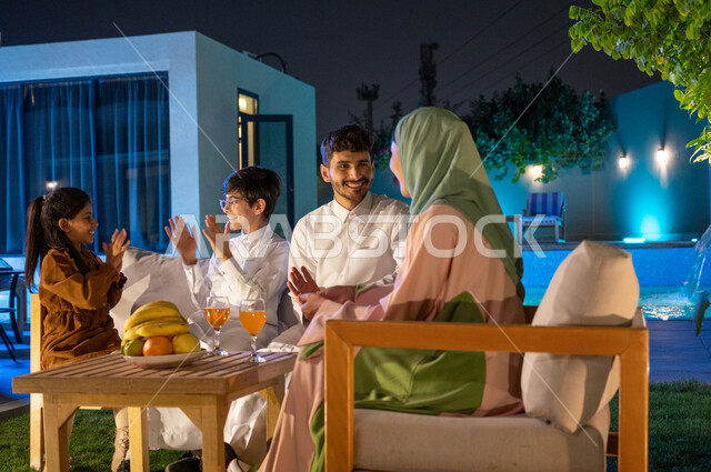 قضاء اوقات ممتعة باللعب والتسلية بين الاخوة، مفهوم المحبة والترابط الاسري، زوجان عربيان خليجيان سعوديان يقومان بتبادل الاحاديث في جلسة عائلية مسائية في احدى الشاليهات الفاخرة، فلل وشقق سكنية راقية في السعودية، اجواء اسرية مليئة بالسعادة و السرور