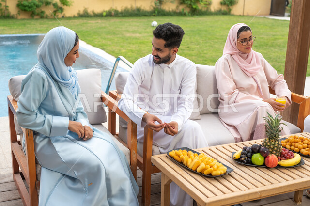 تبادل أطراف الحديث مع الأشقاء، الاستمتاع والسرور بالجلسات الهادئه، مفهوم الأسره السعوديه المترابطه، الاستقرار والأمان العائلي، تناول العصائر الباردة، الاستمتاع في العطلة الصيفيه مع الأفراد في  أحد المنتجعات، عائلة عربيه خليجيه سعودية تقضي أوقات ممتعه في الخارج