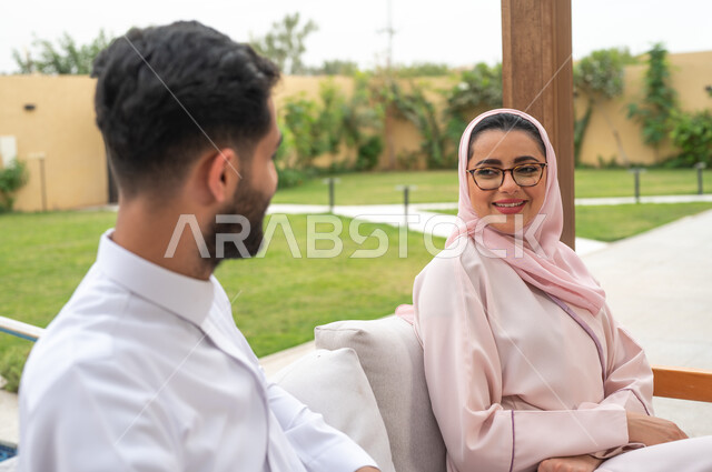 اجواء مليئة بالمحبة والود ،قضاء عطلة نهاية الاسبوع في أحد المنتجعات، مفهوم العلاقات الزوجية الناجحة السعيده، الاستمتاع في أوقات الفراغ في أحد الشاليهات، التنزه في الهواء الطلق ، صورة مقربة لزوجان عربيان خليجيان سعوديان يقومان بتبادل الأحاديث والدردشات