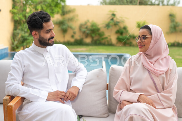 قضاء عطلة نهاية الاسبوع في أحد المنتجعات، مفهوم العلاقات الزوجية الناجحة السعيده، الاستمتاع في أوقات الفراغ في أحد الشاليهات، التنزه في الهواء الطلق ،زوجان عربيان خليجيان سعوديان يقومان بتبادل الأحاديث والدردشات، اجواء مليئة بالمحبة والود