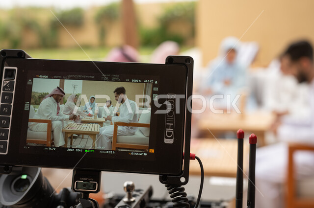 قضاء أوقات ممتعة مع الأهل والأصدقاء في الإجازة الصيفية، أنشطة ترفيهية وألعاب مسلية، خلف الكواليس لجلسة تصوير لعائلة عربية خليجية سعودية تلعب لعبة جينغا في الهواء الطلق، رص الألواح الخشبية، لقطة مقربة لكاميرا حديثة ومطورة، رجلان عربيان سعوديان يلعبان لعبه الورق.