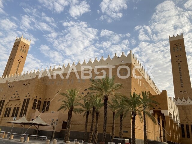 معالم دينية اسلامية مشهورة, الطراز التراثي القديم لبناء الجوامع في السعودية, الفن الهندسي المعماري لمبنى مسجد بريدة الكبير في وسط الديرة بمنطقة القصيم, السماء الملبدة بالغيوم القطنية البيضاء في وضح النهار, أشجار النخيل المزروعة في طرقات المنطقة