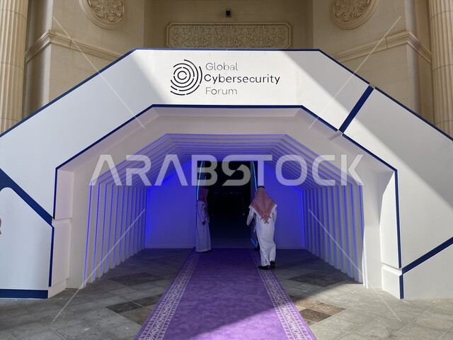 الفن الهندسي المعماري للمباني والفنادق في السعودية, صورة من الخلف لرجل عربي خليجي سعودي يرتدي الثوب التقليدي والشماغ يدخل لقاعة المنتدى العالمي للامن السيبراني في مدينة الرياض, التعرف على اساسات حماية المعلومات ومواكبة الشراكات والحوارات للقطاع الأمني الدولي
