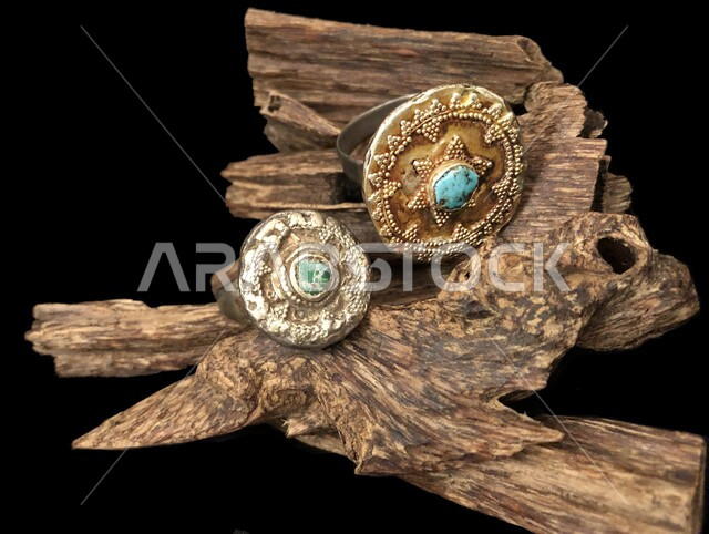 جواهر فضيه ثمينه، استخدام الزمرد والياقوت والاحجار الكريمه في صناعة الحلي والإكسسوارات الأثرية ، مجموعه من الخواتم التقليديه القديمه على قاعدة خشبية، منتجات شعبيه وطنيه سعوديه، مجوهرات نجديه محليه تراثيه، خلفية سوداء .