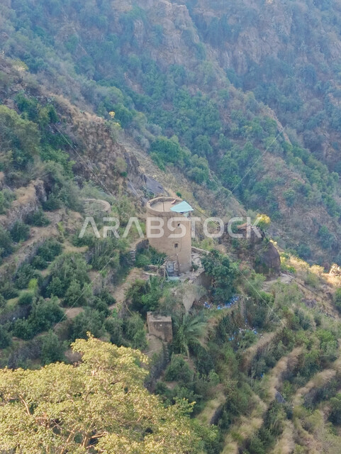 Ancient ancient houses and residential buildings in the mountains of Faifa Governorate in Jazan, green agricultural terraces and trees on the mountain peaks and heights, natural tourist attractions and places in the Kingdom of Saudi Arabia, nature background