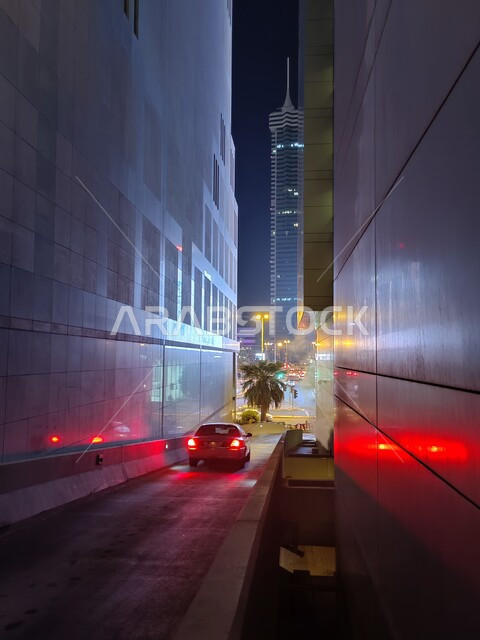 التجهيزات الطرقية وتوفير الإنارة الليلية في شوارع مدينة المنامة، طرق وشوارع مملكة البحرين، أماكن ومعالم سياحية مشهورة، صورة من الخلف لسيارة اثناء مرورها من ممر منزلق لإحدى المباني في وقت الليل