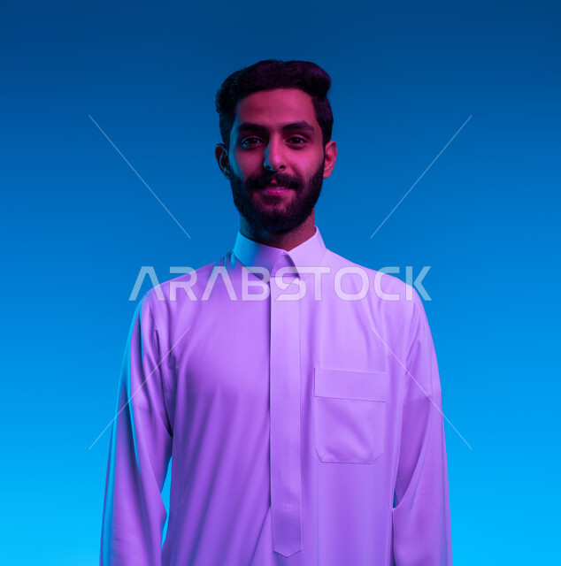 A personal photo for official documents, concern for external appearance, the concept of masculinity and elegance, a close-up portrait of a smiling Saudi Arab Gulf man wearing a traditional dress looking at the camera with gestures of self-confidence and cheerfulness, standing upright and steady, blue background