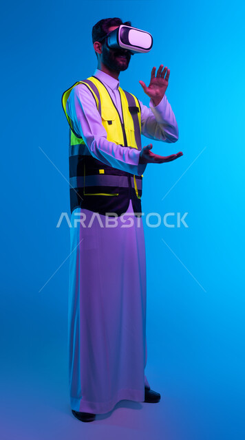 Saudi future vision 2030, interaction with virtual engineering, portrait of a Saudi Arabian Gulf engineer wearing a work jacket and virtual reality glasses holding an element, growth and development of the engineering field through VR glasses, full-body portrait, blue background