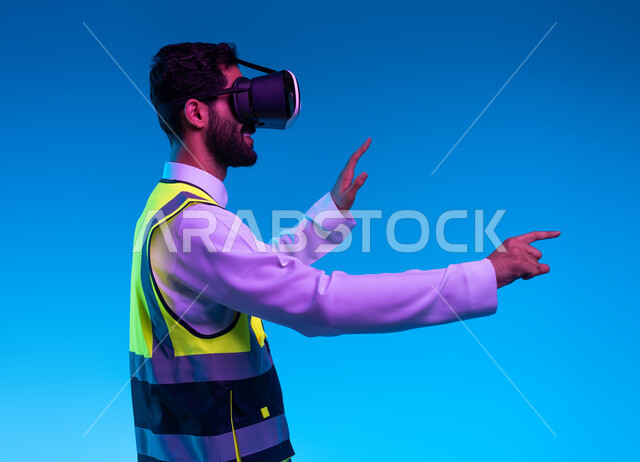 Simulation of imaginary reality, use of technology in engineering fields, interaction with virtual engineering, future vision 2030, close-up portrait from the side of a Saudi Arabian Gulf engineer wearing a work jacket and VR glasses, an element pointing, blue background