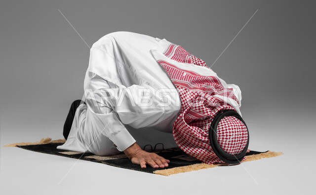 التقرب من الله تعالى بأداء الفرائض والتزام أوامره, بورتريه لرجل عربي خليجي سعودي كبير بالسن يرتدي الشماغ والثوب التقليدي يسجد لله تعالى, أهمية الالتزام بالصلاة على وقتها, مفهوم أركان الإسلام, إسلاميات وعبادة, خلفية رمادية