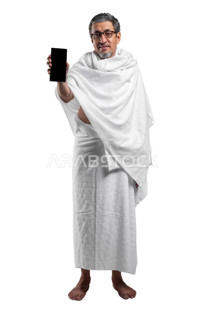 Mobile phone applications and programs for Hajj and Umrah instructions, a portrait of a smiling elderly Saudi Arabian Gulf man wearing Ihram clothes displaying