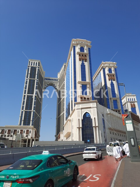 Car traffic on Ibrahim Al-Khalil Street in the daytime, the advanced architectural art of towers and tourist buildings, the Jabal Omar complex adjacent to the Grand Mosque in Mecca, the luxury Conrad hotels and resorts in Saudi Arabia